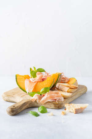 Fresh melon with prosciutto and basil. Antipasti, Italian food. Top view on white stone table with copy space for your textの写真素材
