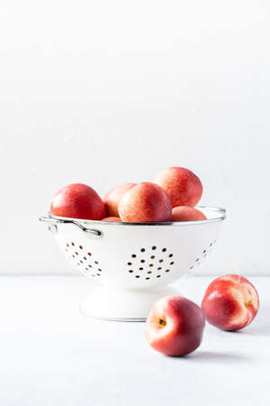 Fresh peaches and nectarines for a delicious Breakfast in a white iron bowl on a white background. The concept of delicious and healthy food. Copy space.の写真素材