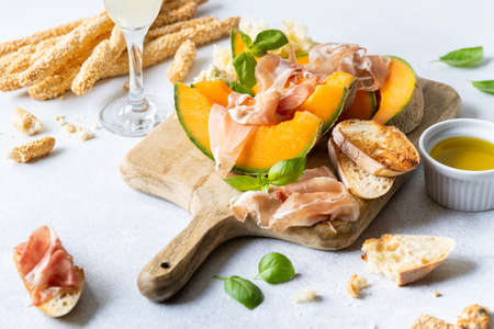 Fresh melon with prosciutto and basil. Antipasti, Italian food. Top view on white stone table with copy space for your textの写真素材