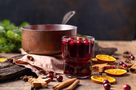 Hot mulled red wine drink with citrus, apples, cinnamon sticks, cloves and anise in cooking pan on...