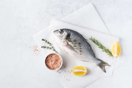Seafood. Fresh raw dorado fish with spices. Ingredients for cooking or grill on cutting board. Top view, copy spaceの写真素材