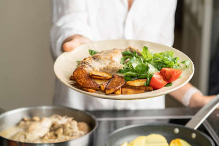 The hands of a man cook potatoes in a frying pan. Family dinnerの写真素材