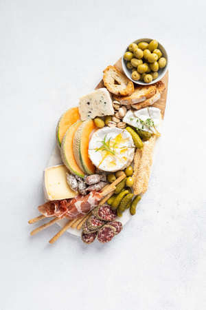 Cheese platter with different cheeses, grapes, honey. Appetizers table with antipasti snacks. Top view, flat layの写真素材