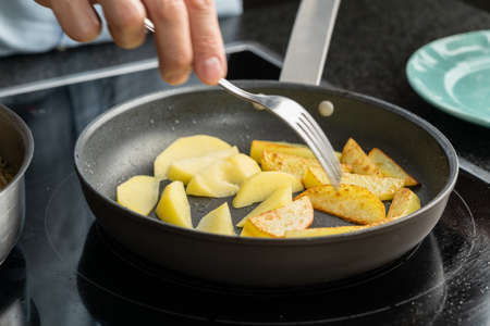 The hands of a man cook potatoes in a frying pan. Family dinnerの写真素材