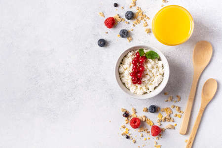 Farm cottage cheese in a white plate with berries and fruits. A healthy breakfast, a source of protein and useful substances. Gray background, top view.の写真素材