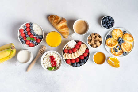 Morning served breakfast set: pancakes, porridge, cottage cheese, granola, muesli, orange juice, tea, coffee, fruits and berries.の写真素材