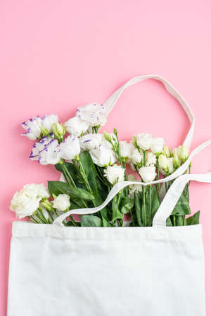 The composition of flowers and bags. A gift and flowers on a pink background. Womens Day, a holiday. Flat sunbed, top view, copy space.の写真素材