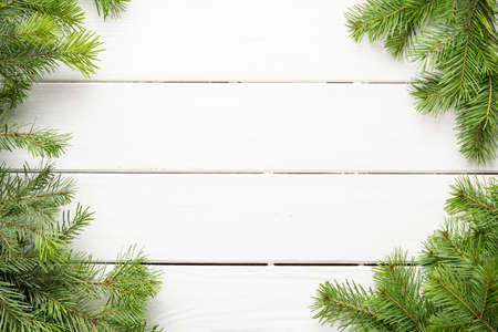 Green branches of the Christmas tree on a white wooden background, merry Christmas and New Year....