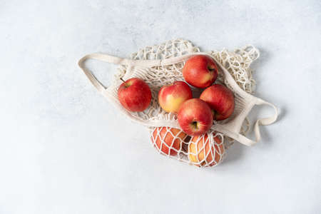 Fresh red apples in a hand bag on a gray background. Top viewの写真素材