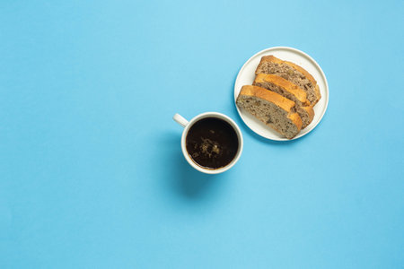 Nut cake and black coffee on sky blue background.