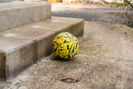 Yellow football resting on stairs in daylight.の写真素材
