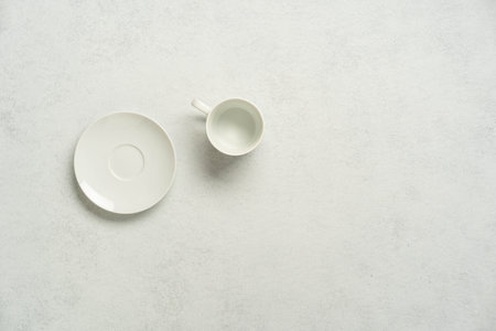 Empty white plate and cup on clean minimalist background.の写真素材
