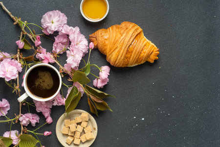 Croissant and coffee with cherry blossoms on dark background. High quality photoの写真素材