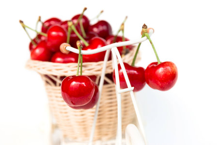 Cherries in decorative basket on a bicycle, isolated on white background. Decorative image, printed...