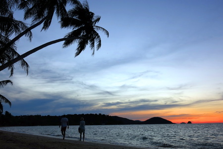 a couple walking on the beach during sunsetの写真素材