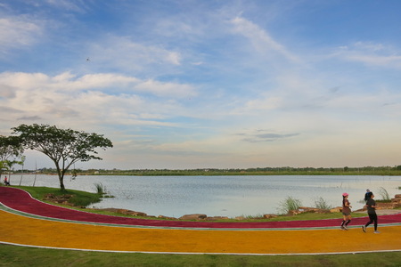 Khon Kaen,Thailand-August 2018: people running on the running lane in the park beside the lake, with...