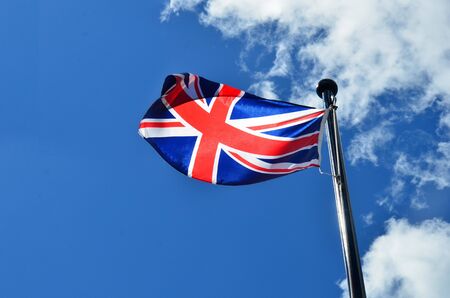 An image of an old British flag flying against a bright blue sky.の写真素材