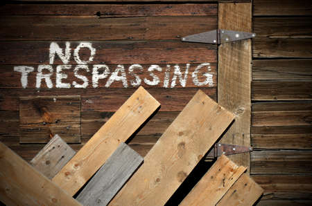 An image of No Trespassing written in white on the side of an old weathered barn.