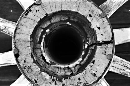 A black and white image of the hub of an old wooden wagon wheel.の写真素材
