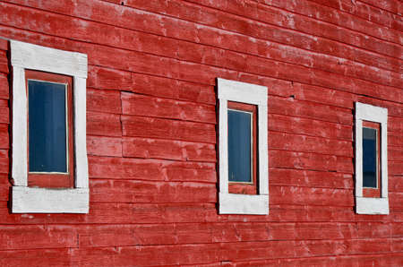 An abstract image of three white windows on an old red building.の写真素材