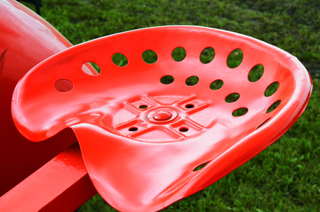 An image of a bright red metal tractor seat.の写真素材
