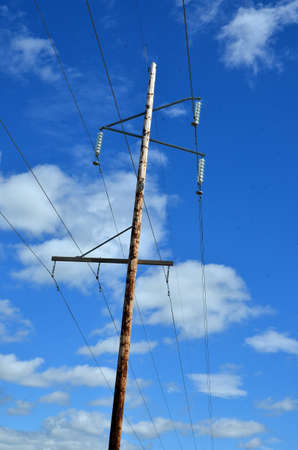 An image of a power pole and power lines against a blue sky.