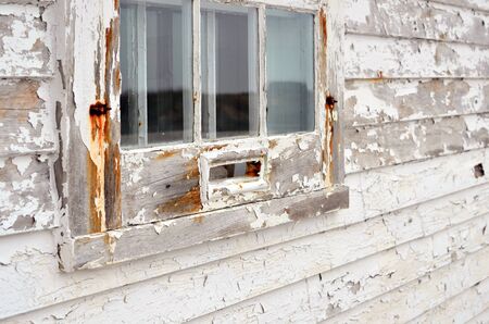 An image of an old wooden window with white peeling paint.の写真素材