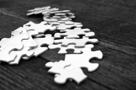 An image of stacked white puzzle pieces on a wooden table.