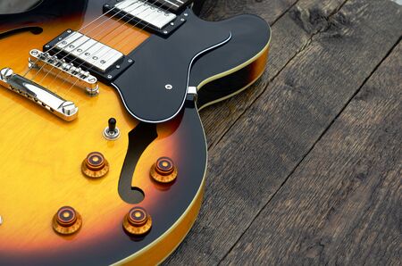 A low angle view of a yellow electric guitar on a wooden table top.