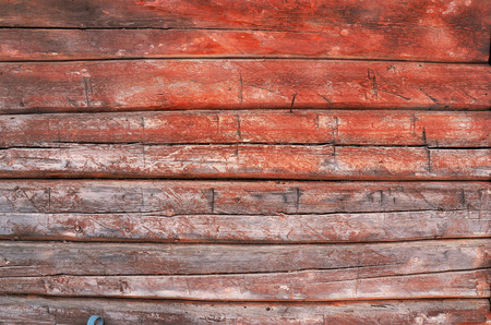 An image of old weathered wood with peeling red paint.の写真素材
