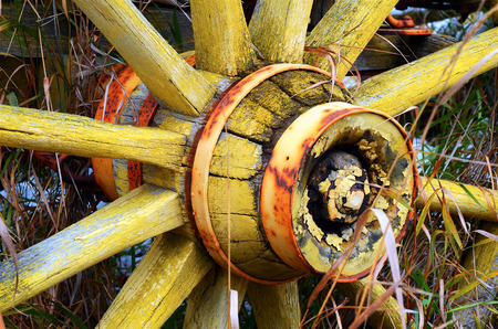 An abstract image of an old wooden wagon wheel with peeling yellow paint.の写真素材