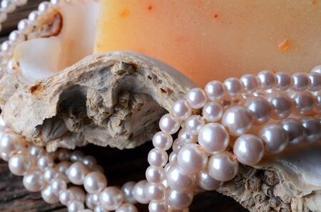 A close up view of a string of pearls on an oyster shell with a bar of homemade oatmeal soap.
