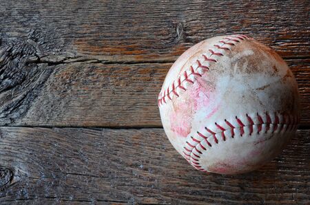 A top view image of an old used leather baseball on a rough wooded surface.の写真素材