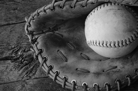 A black and white image of an old used baseball and baseball glove.の写真素材