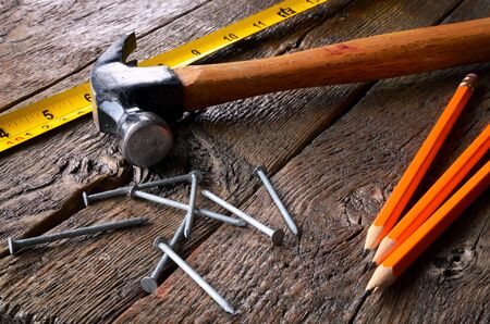 A close up image of an old wooden hammer and several nails on a workbench.の写真素材