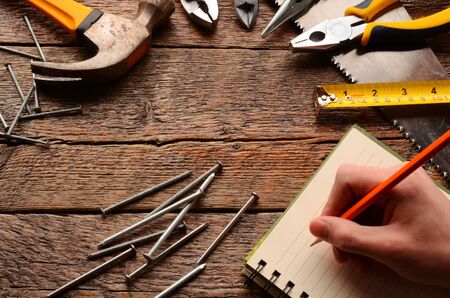 A top view image of various hand tools on a wooden work bench.