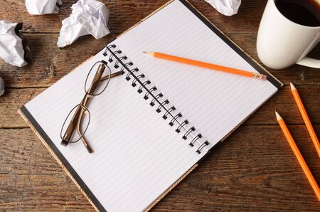 A top view image of an open notebook on an old wooden desk top.