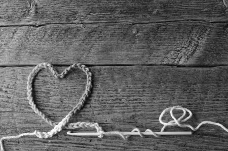 A top view image of a crochet heart symbols on a wooden table surface.の写真素材