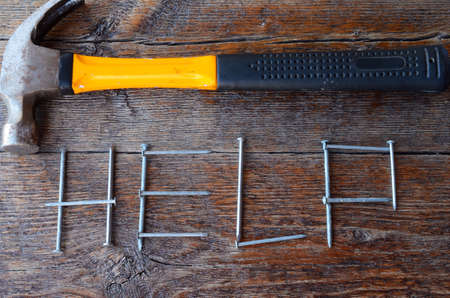 A top view image of the word help spelled out in nails on an old wooden workbench.の写真素材