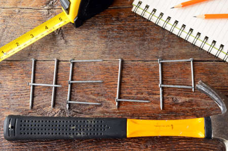 A top view image of the word "help" written out with nails on an old wooden workbench.の写真素材