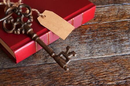 A top view image of antique cast iron keys and a red book on a wooden bench.の写真素材