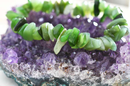 A close up image of a jade bracelet charging on an amethyst geode.