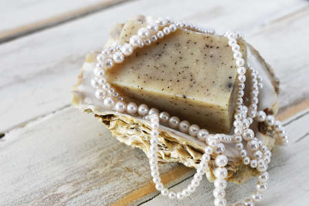 An image of organic hand made soap on an oyster shell and which wooden background.の写真素材