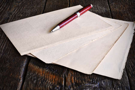 A low angle image of several sheets of vintage writing paper on an old wooden table top.