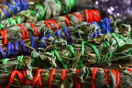 A close up image of several home made smudge sticks wrapped in brightly colored string.