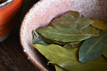 A close up image of dried bay leaves in a hand made pottery bowl.