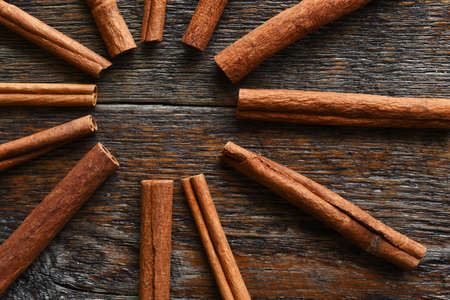 A close up image of several tasty cinnamon sticks on a dark wooden table.