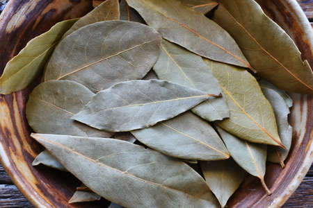 A top view image of dried bay leaved in a hand made pottery bowl.