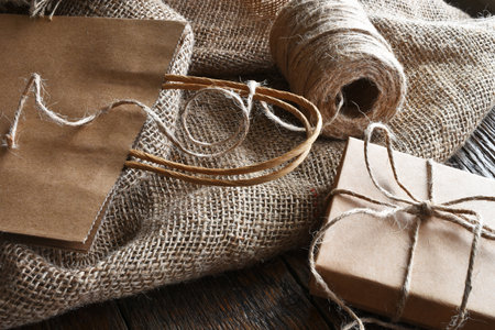 A close up image of a vintage style  brown paper bag and box tied with burlap thread.の写真素材
