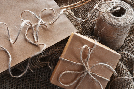 A close up image of a vintage style  brown paper bag and box tied with burlap thread.の写真素材